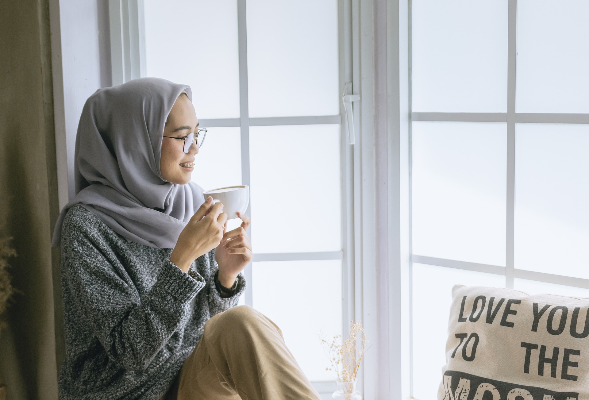 A woman  sitting by the window with a cup of coffee