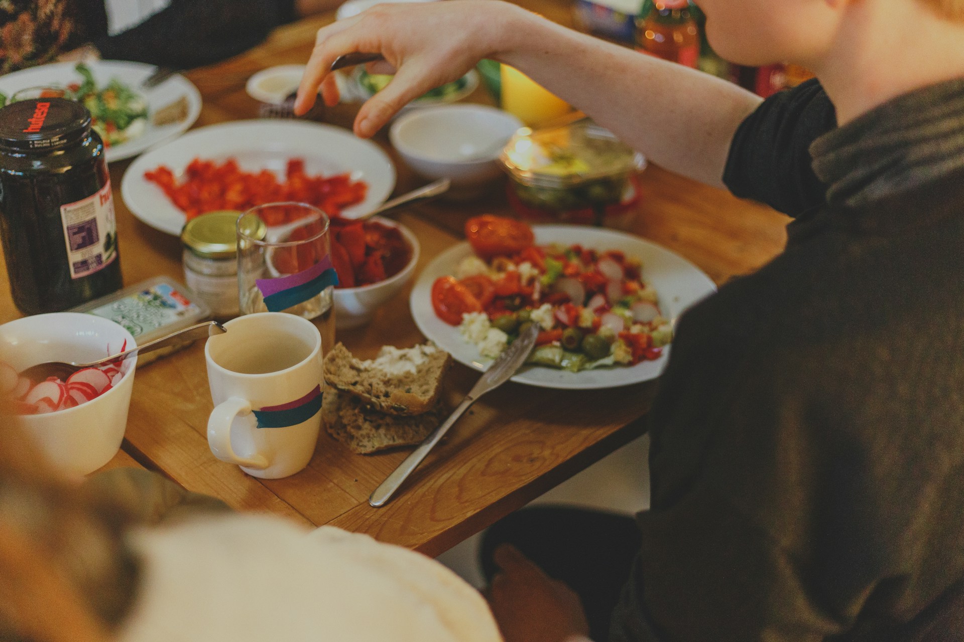 A person sitting in front of a table with various veggies and salad