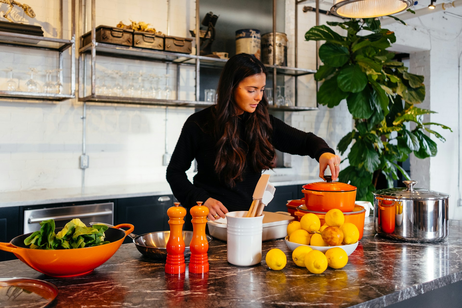 Woman standing in front of a table of fruits, holding a pot lid