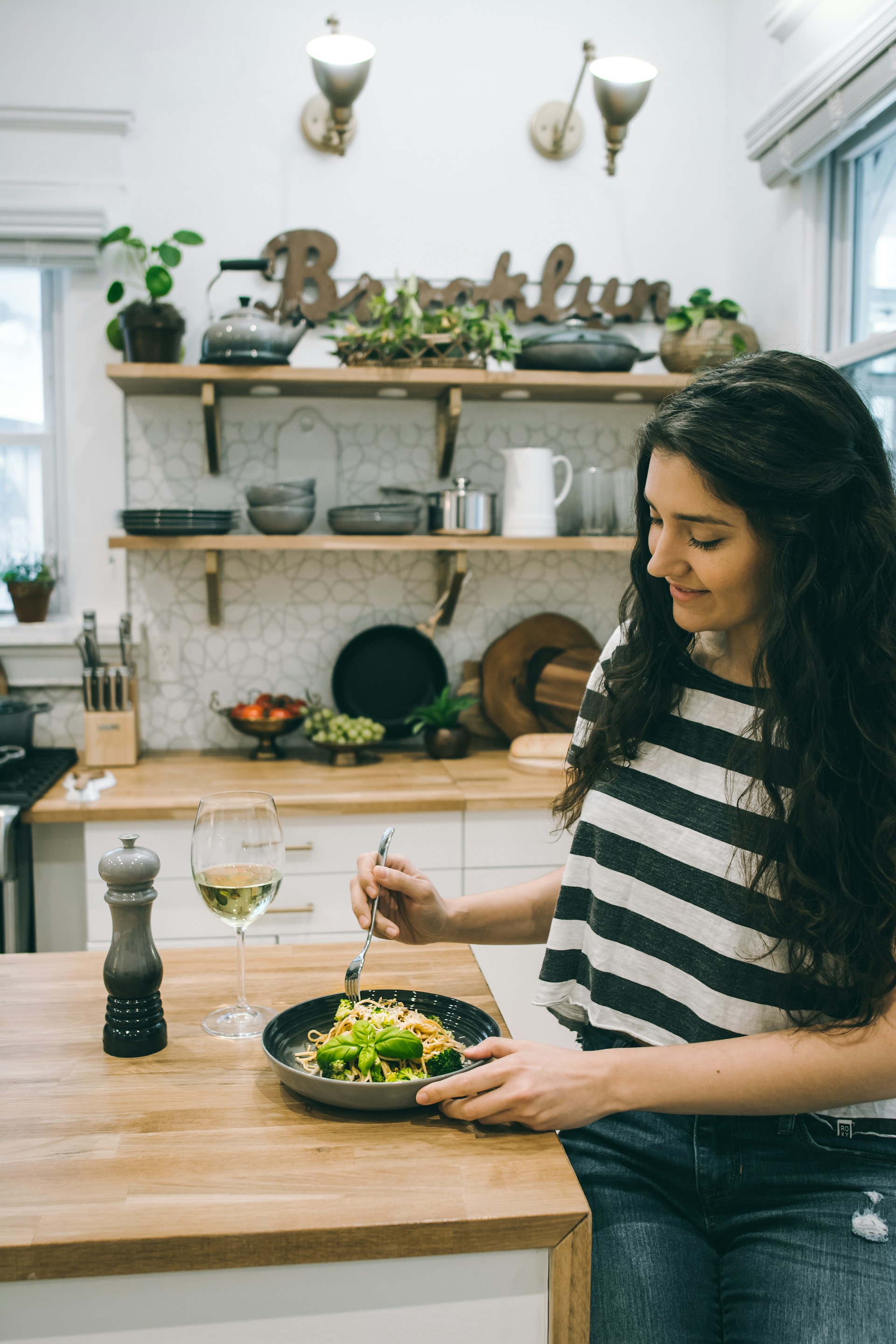 A woman standing of a table with a plate of noodles and veggies